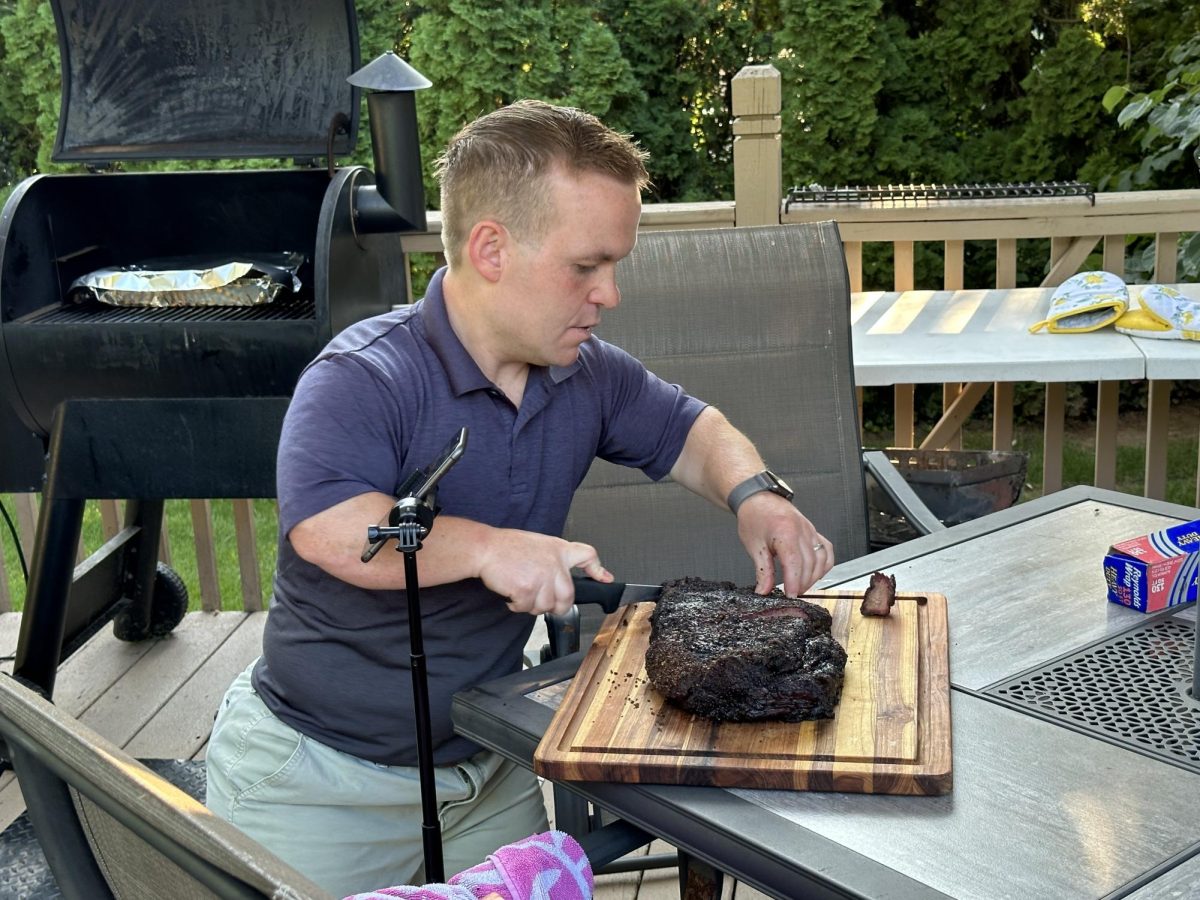Mr.+Bell+in+action%E2%80%94+slicing+a+steak+while+being+filmed+by+his+phone+on+a+tripod.%0A