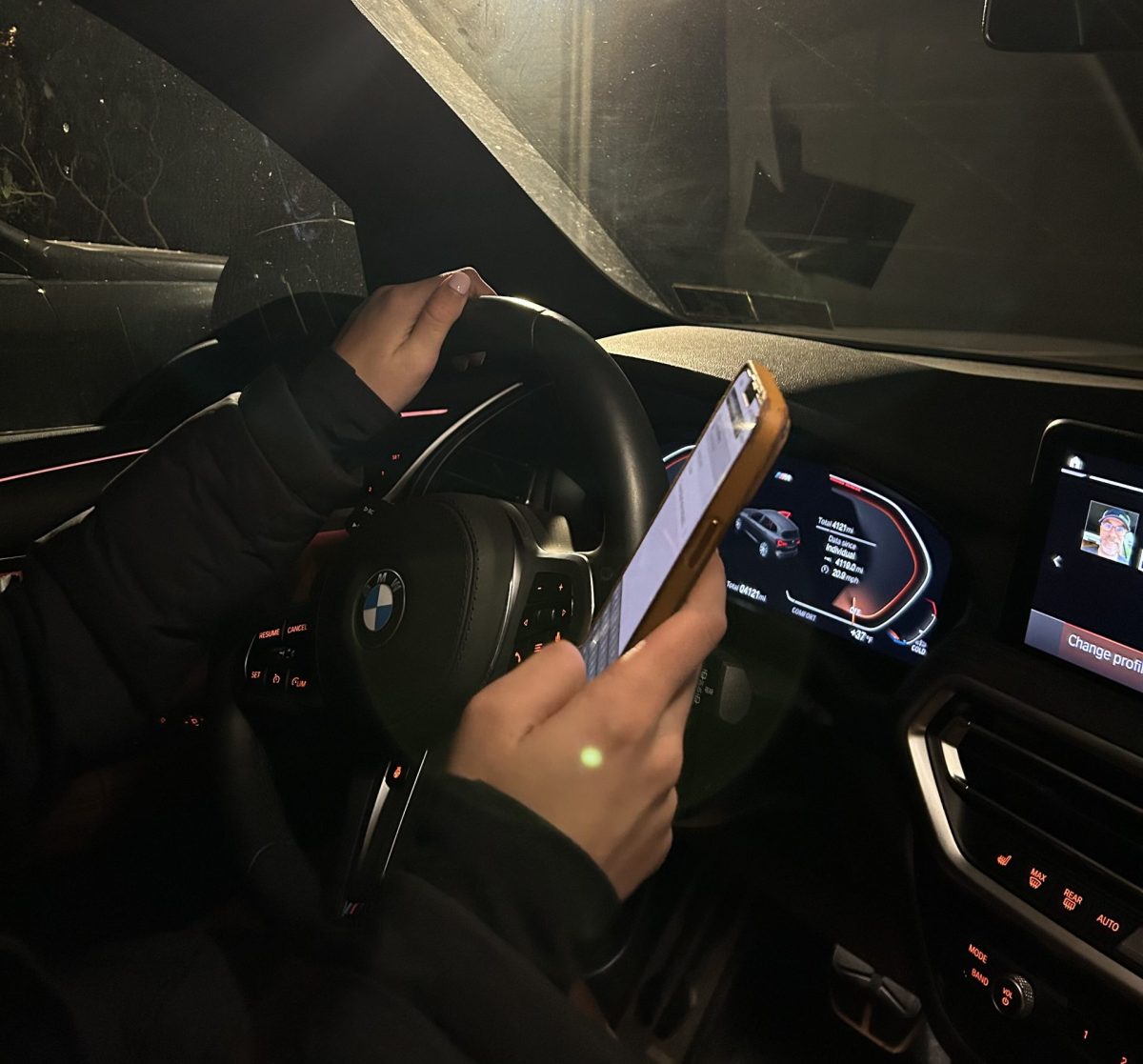 Teen driver using phone while driving their car.