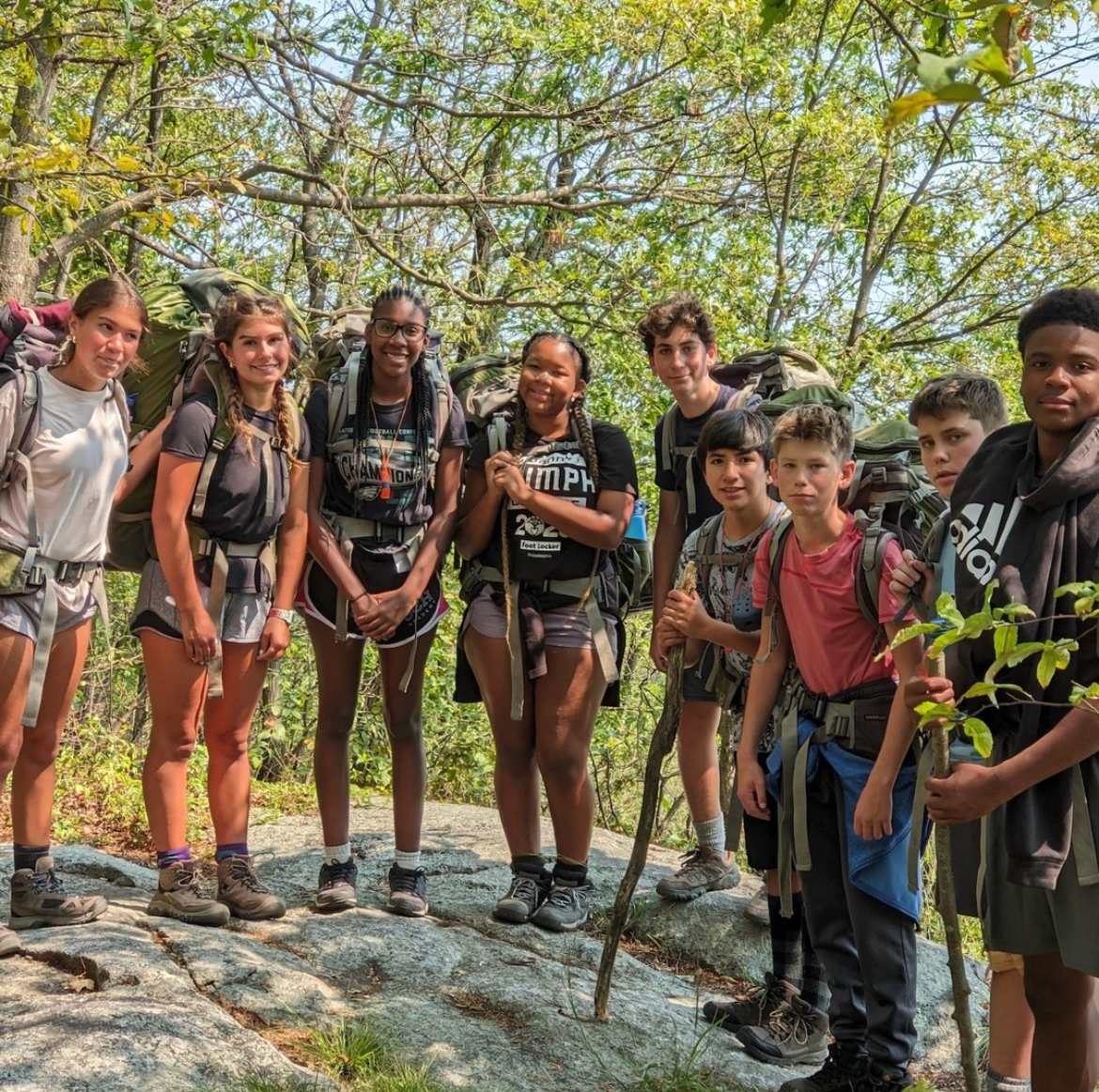 A group of freshmen gather on a cliff for a photo during Outward Bound.