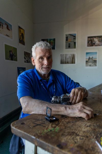 Pete Capano holds camera while working at his desk