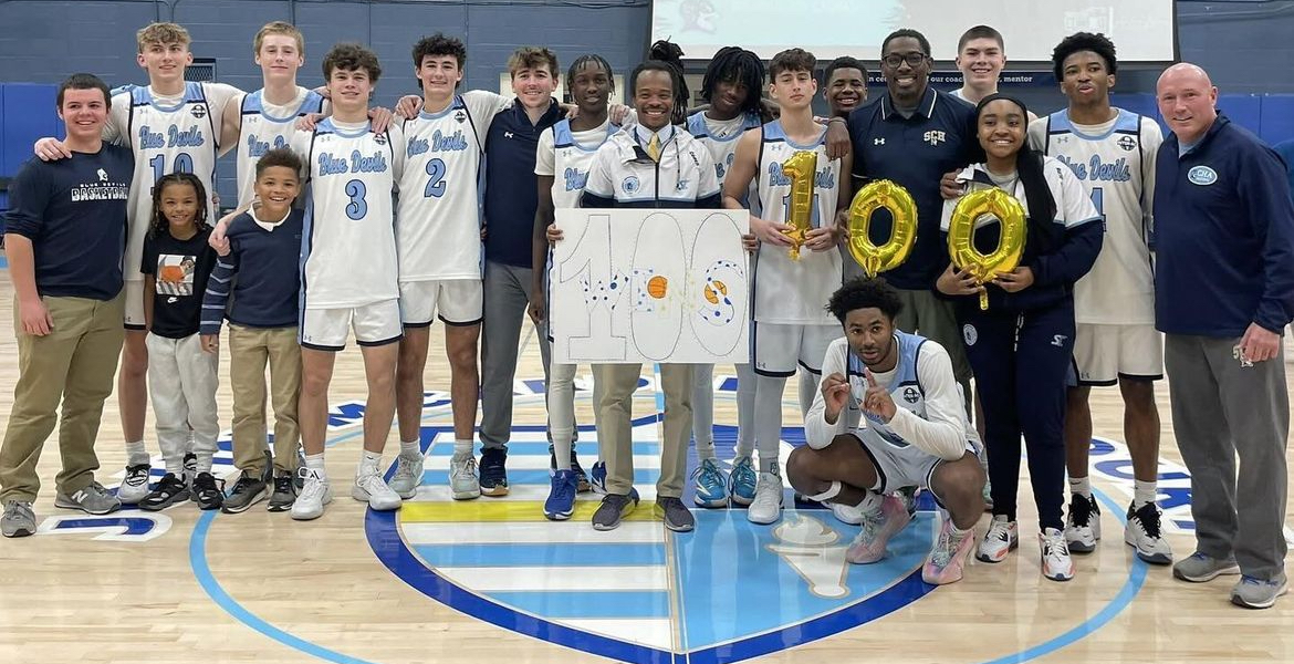 Coach Jules and the boys basketball team celebrate his 100th win