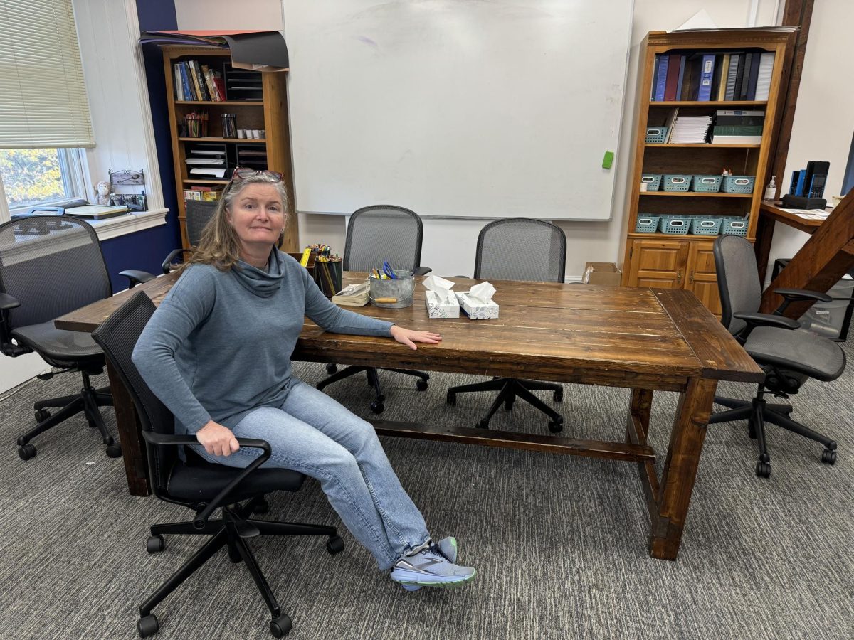 Ms. O sitting at table she built herself.