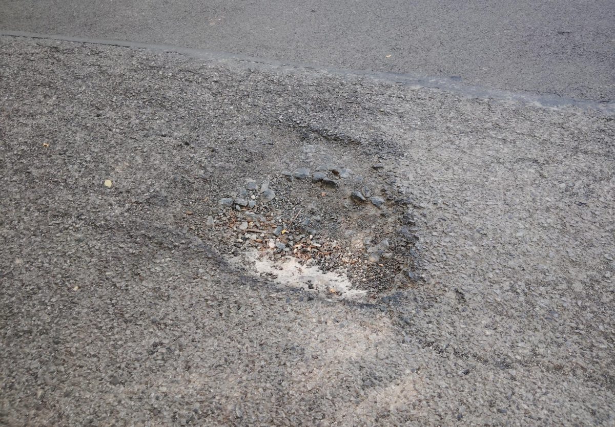 Deep pothole on the middle of the road behind the Early Childhood Center, nearby entrance to the Rec.